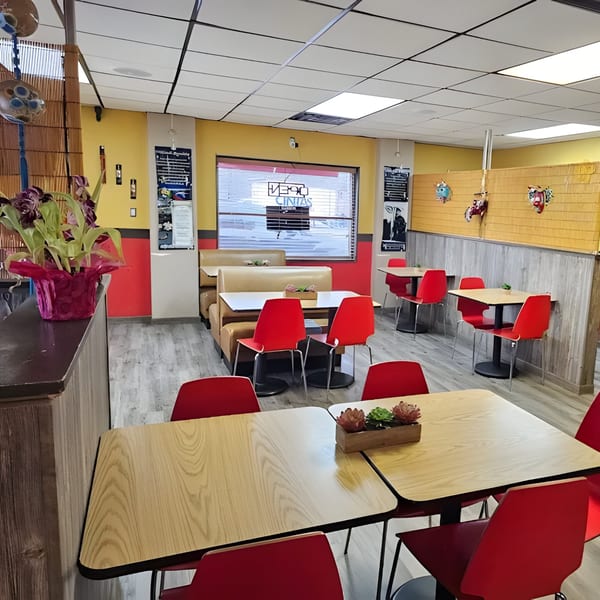 Interior of La Taguara Bar & Grill, featuring red chairs, light wood tables, and yellow walls.